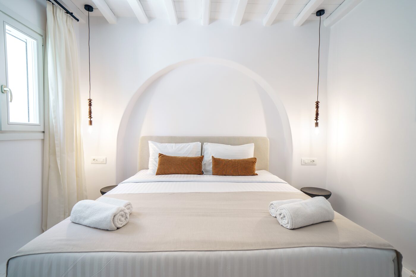 Bedroom with a whitewashed arched headboard niche and pendant lighting at Primadonna