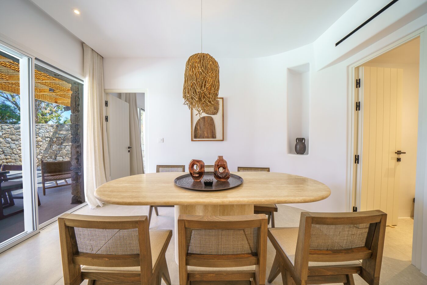 Dining area with a round table and woven pendant beside the open kitchen, Mykonos