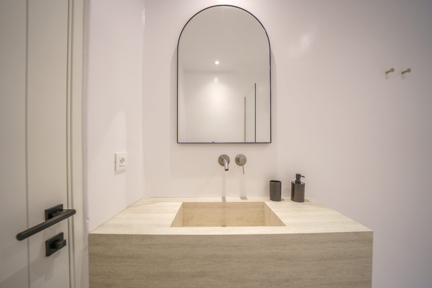 Villa Afrodite spa bathroom with a freestanding travertine tub and arched mirror