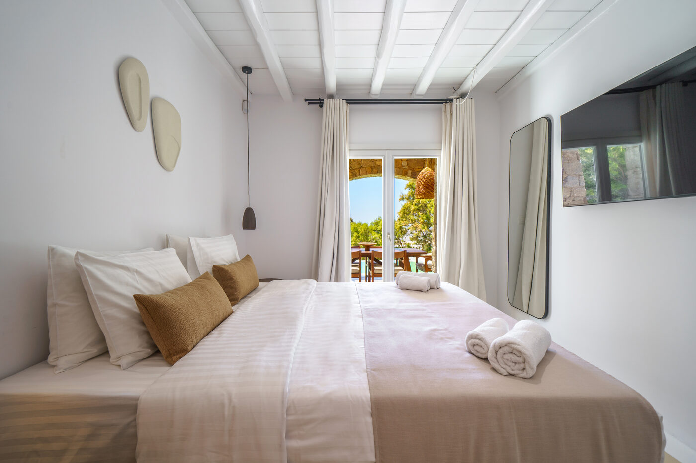 Villa Afrodite master bedroom with a sea-view window and natural linen bedding