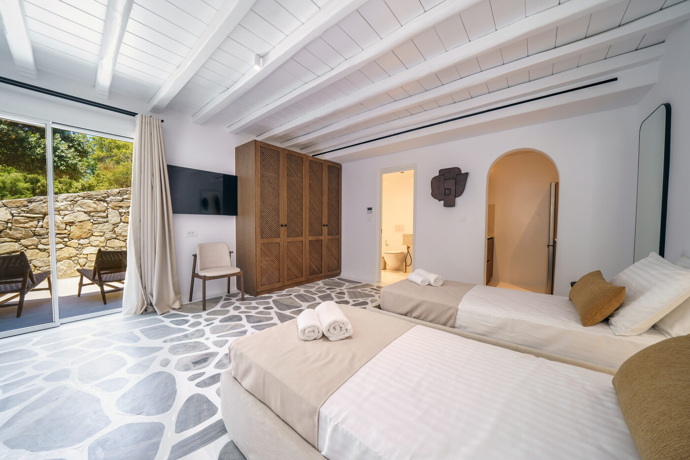 Villa Afrodite bedroom with a Cycladic pebble-stone floor opening to a private terrace