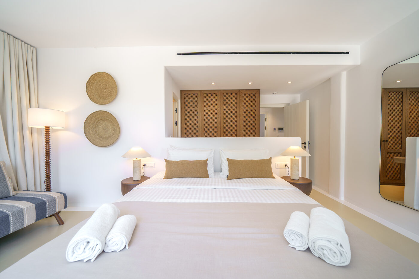 Villa Afrodite bedroom with woven rattan wall discs and bedside lamps