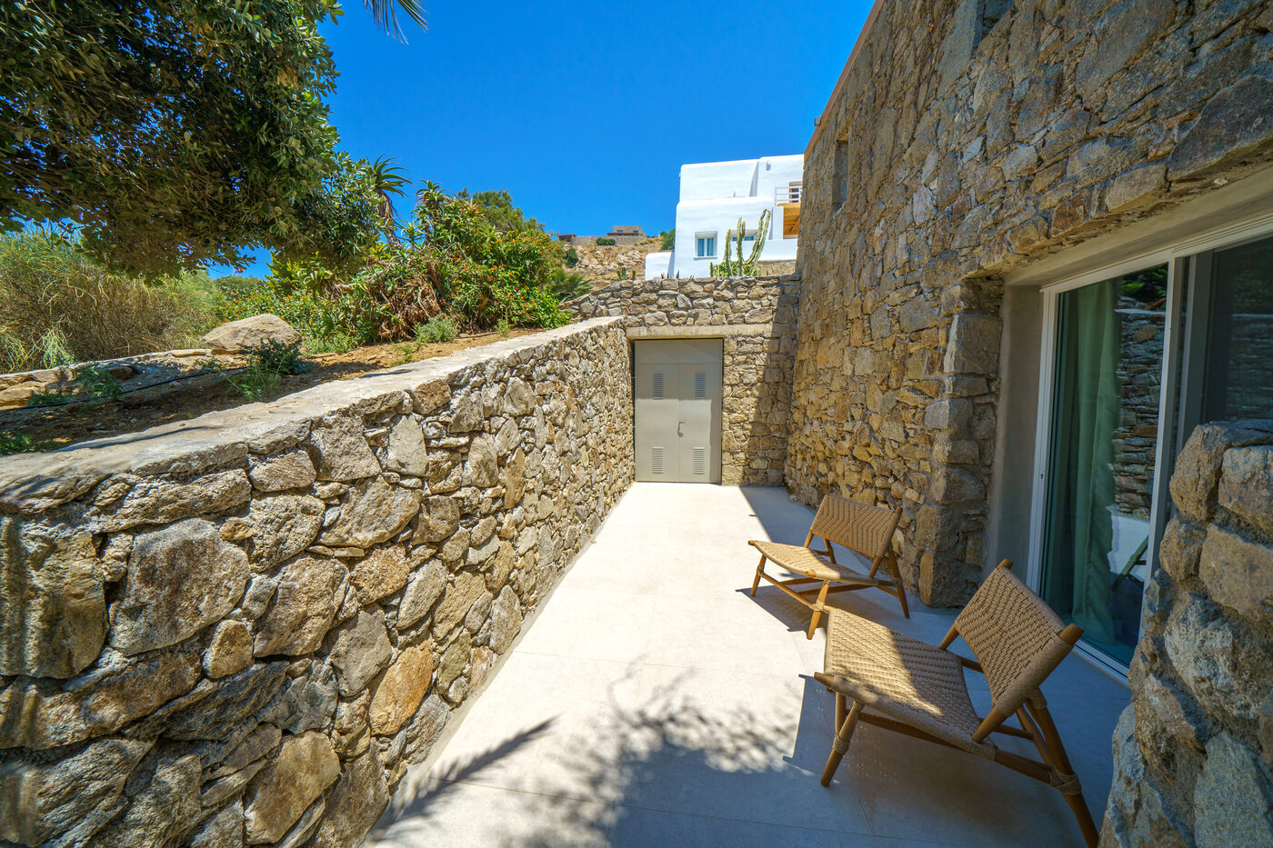 Villa Afrodite stone-walled terrace and loungers set into the Mykonian hillside