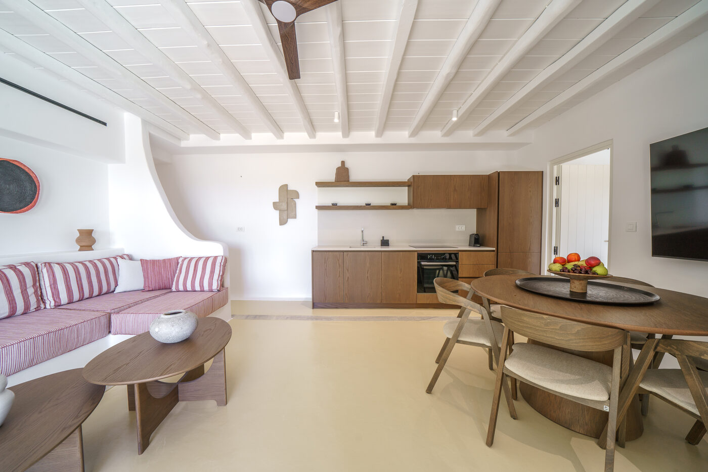 Villa Afrodite open-plan living room, dining table and kitchen with a mauve built-in sofa
