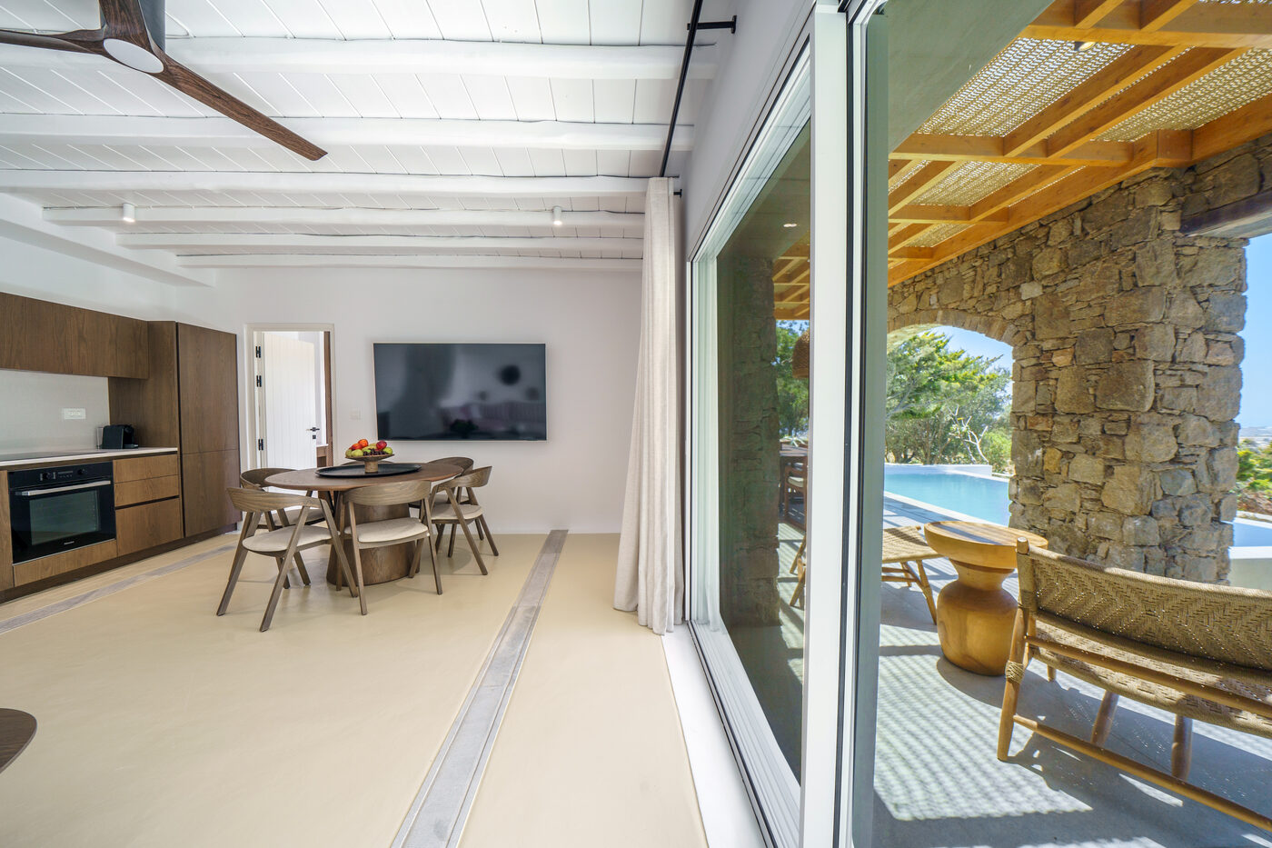 Villa Afrodite living and dining area opening through sliding doors to the pool terrace
